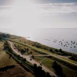 Drohnenaufnahme: Blick auf Deich, Ostsee und kleine Boote auf dem Wasser am Morgen