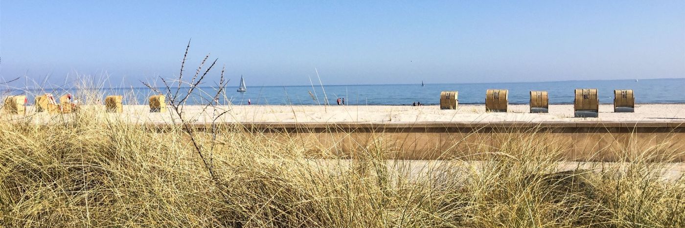 Strand mit Strandkörben, Sand, Meer und klarem Himmel im Hintergrund
