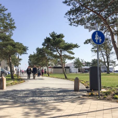 Fußweg mit Menschen, Bäumen und Verkehrszeichen Am Strande