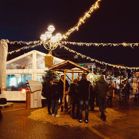 Menschen auf einem weihnachtlich beleuchteten Markt am Abend