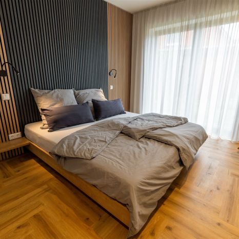 Modernes Schlafzimmer mit Holzbett und großer Fensterfront mit Gardinen