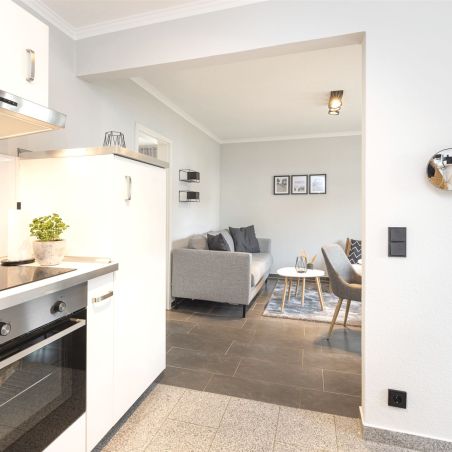 Moderner Küchenbereich mit Blick auf ein Wohnzimmer mit Sofa und Stühlen