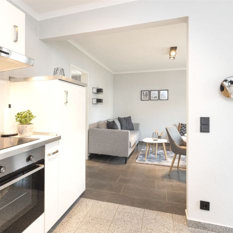 Moderner Küchenbereich mit Blick auf ein Wohnzimmer mit Sofa und Stühlen