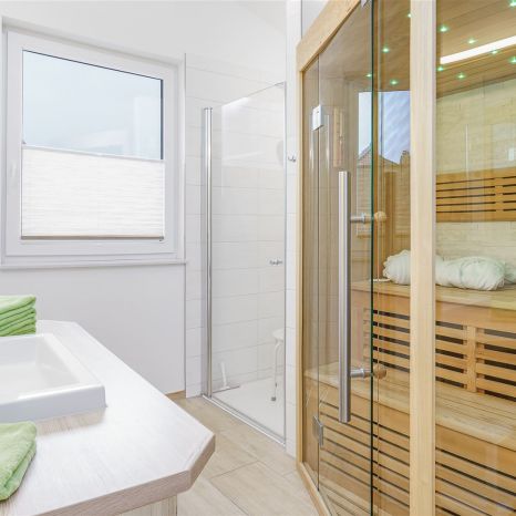 Modernes Badezimmer mit Sauna, Fenster, Dusche, Waschbecken und grünen Handtüchern